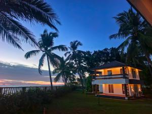 a house on the beach with palm trees at Kappad Beach Resort in Kappad