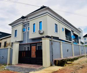 a white house with blue windows and a garage at Welcome to Originclicks Apartments! in Ebute Ikorodu