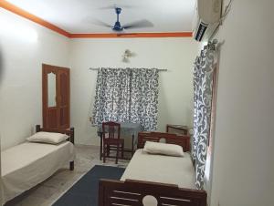 ein Schlafzimmer mit zwei Betten, einem Tisch und Stühlen in der Unterkunft Shield Guest Accommodation in Pudunagaram