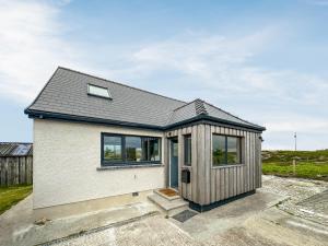 a small white house with a black roof at Grianan in Eriskay