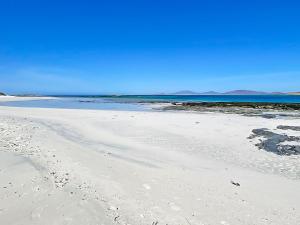 a beach with footprints in the sand and the ocean at Grianan in Eriskay +15 photos