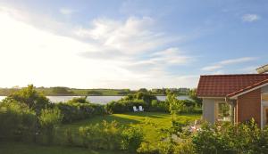 a house with a yard with a lake in the background at Fliederuferhaus in Kosel