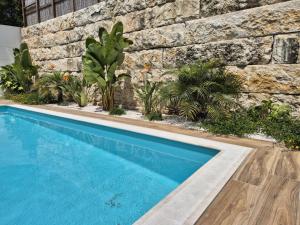 a swimming pool in front of a stone wall with plants at Casa Encanto da Foz - BY SCH in Foz do Arelho