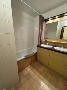 a bathroom with two sinks and a tub and a mirror at Artemis 402 2 chambres et coin montagne in Brides-les-Bains