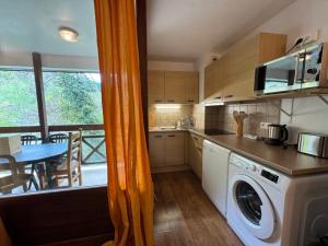a kitchen with a balcony with a table and a washing machine at Artemis 402 2 chambres et coin montagne in Brides-les-Bains