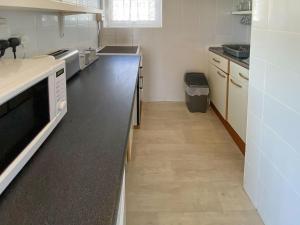 a kitchen with white counters and a black counter top at Sea Pearl in Kessingland