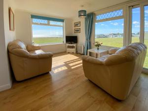 a living room with two leather chairs and a television at Sea Pearl in Kessingland