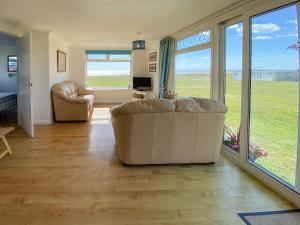 a living room with a couch and chairs and sliding glass doors at Sea Pearl in Kessingland