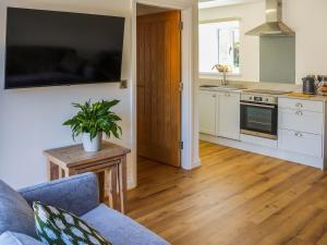 a living room with a blue couch and a kitchen at Bodlyn - Uk48861 in Llanddwywe
