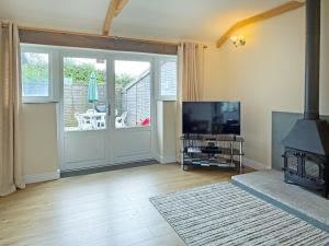 a living room with a television and a sliding glass door at Tresidder Barn in Constantine +10 photos