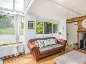 a living room with a leather couch and windows at Heath Hills in Okehampton