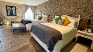 a bedroom with two beds and a stone wall at Loft Giofiel in Santeagueda