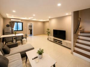a living room with a couch and a tv at Holi PTY Hotel in Ban Huai Yai