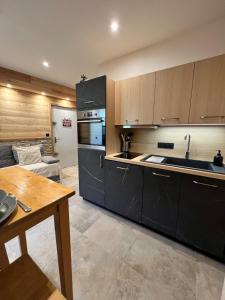 a kitchen with black cabinets and a living room at Appartement moderne style chalet in Le Monêtier-les-Bains