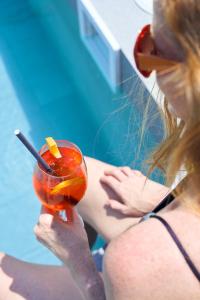 a woman sitting next to a pool holding a drink at Gran Hotel Havana 4Sup by Escampa Hotels in Barcelona
