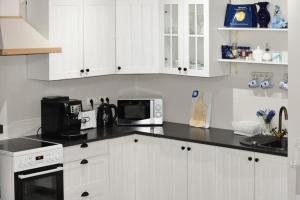 a kitchen with white cabinets and a black counter top at Paju Apartment in Võru