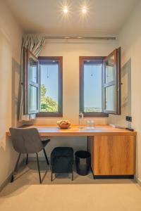 a kitchen with a desk with a chair and two windows at Terra Petra Meteora in Kalabaka