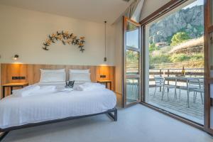 a bedroom with a bed and a large window at Terra Petra Meteora in Kalabaka +53 photos