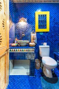 a blue tiled bathroom with a toilet and a sink at Al manar in Oulad Akkou