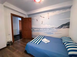 a bedroom with a blue bed with a painting on the wall at Vila Iulia in Eforie Nord