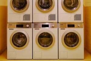 four washers and dryers are lined up in a room at Ember Locke Kensington in London +16 photos