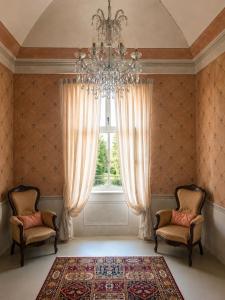 a room with a chandelier and two chairs and a window at Castello di Morozzo Guest House in Morozzo