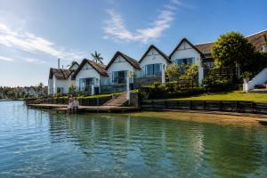 a woman sitting on a dock in front of a house on the water at CANAL GUEST HOUSE - Waterfront Boutique B&B in St Francis Bay