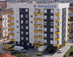 an apartment building with yellow balconies in a parking lot at Stan na dan Alex in Bijeljina