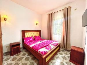 a bedroom with a bed with pink sheets and a window at Résidence T&M ODZA Yaoundé Cameroun in Méhandan