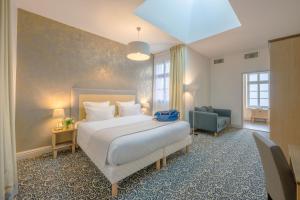 ein Hotelzimmer mit einem Bett und einem Stuhl in der Unterkunft Hotel Heritage in Cognac