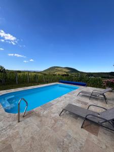 a swimming pool with two lounge chairs next to it at Csernus Doki bor-grillterasza és bungallói in Eger