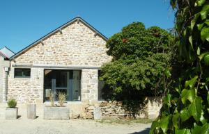 a stone house with a tree in front of it at L'Etable d'Armand in Névez