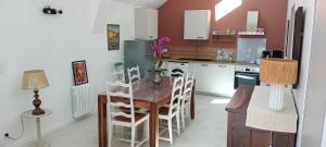 a kitchen with a wooden table and white chairs at L'Etable d'Armand in Névez