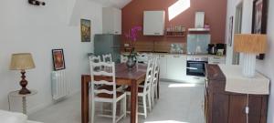 a kitchen with a wooden table and white chairs at L'Etable d'Armand in Névez +13 photos