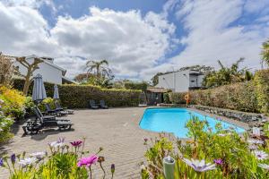 a backyard with a swimming pool and flowers at Quinta De Santana in Rabo de Peixe