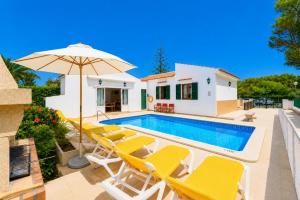 a villa with a swimming pool and yellow chairs and an umbrella at Villa Estrella in Cala en Blanes