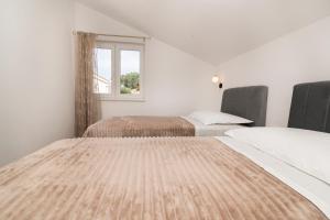 two beds in a room with a window at Apartments Vini in Donji Seget