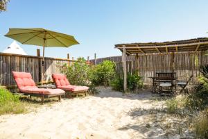 a patio with two chairs and an umbrella at Guesthouse Évasion in Contis-les-Bains