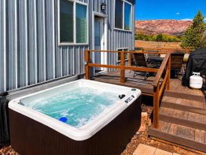 a jacuzzi tub on a deck next to a house at Hot Tub Under Desert Sky, Zion Tiny Home Getaway in Apple Valley +24 photos