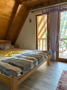 a bedroom with a bed and a large window at Vikendica Vesic Tegare in Bratunac +59 photos