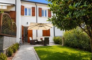 a patio with a table and chairs and an umbrella at CaMagnolia Apartment in Montegrotto Terme +25 photos