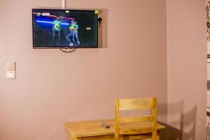 a room with a tv on a wall with a wooden chair at Olivia Green Lodge in Arusha