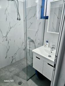 a white bathroom with a shower and a sink at Cozy Family Studio 2 in Ksamil