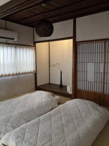 a bedroom with a bed and a window with a vase at 貸切一軒家 祇園House in Matsuyama