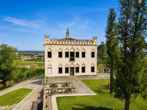 a large white building in a park with a tree at CaMagnolia Apartment in Montegrotto Terme