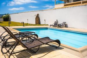 a swimming pool with two chairs next to a building at HANNA Búzios Al Mare Hotel in Búzios +23 photos