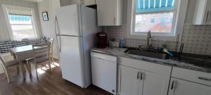 a kitchen with a white refrigerator and a table and a dining room at Oceanfront Townhouse steps to the Beach in Atlantic Beach
