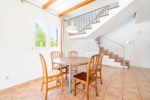 a dining room with a table and chairs and stairs at Villas2meet La Siesta in Cala Romàntica