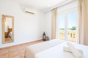 a white bedroom with a large bed and a large window at Villas2meet La Siesta in Cala Romàntica +26 photos