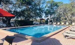 a swimming pool with chairs and a red umbrella at Lifetime of Vacations in Orlando
